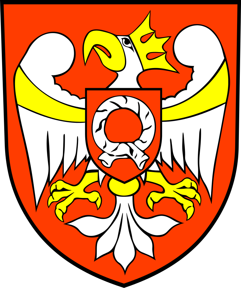 Herb Powiatu Szamotulskiego. Srebrny orzeł ukoronowany złotą koroną, o złotym dziobie zwróconym w prawo, złotych łapach i pazurach, ze złotą przepaską na skrzydłach i złotym pierścieniem spinającym ogon. Orzeł przedstawiony jest na czerwonym tle. Na piersiach orła znajduje się czerwona tarcza i biała pomłość.