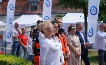 Goście, lekarze i pielęgniarki na terenie Muzeum Zamek Górków przysłuchują się brifingowi medialnemu Ministra Zdrowia 