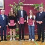 Dyrektor Jan Stefaniak, 3 uczniów ze stypendiami Starosty Szamotulskiego oraz dyrektor  Arkadiusz Mejer na tle czerwonej kotary