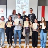 6 uczniów z dyplomami w rękach wraz nauczycielami, którzy stoją za nimi 