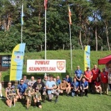 Zdjęcie grupowe uczestników na tle baneru Powiat Szamotulski i i flagach KS Tarcza Szamotuły